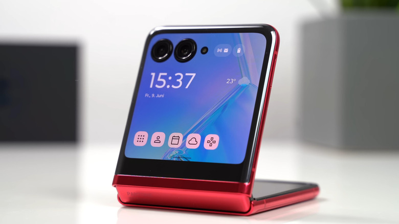 A red Motorola Razr foldable phone partially open with the external display visible