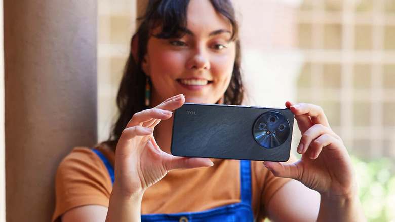 Person holding a TCL 60 XE Nxtpaper phone with the rear cameras visible.