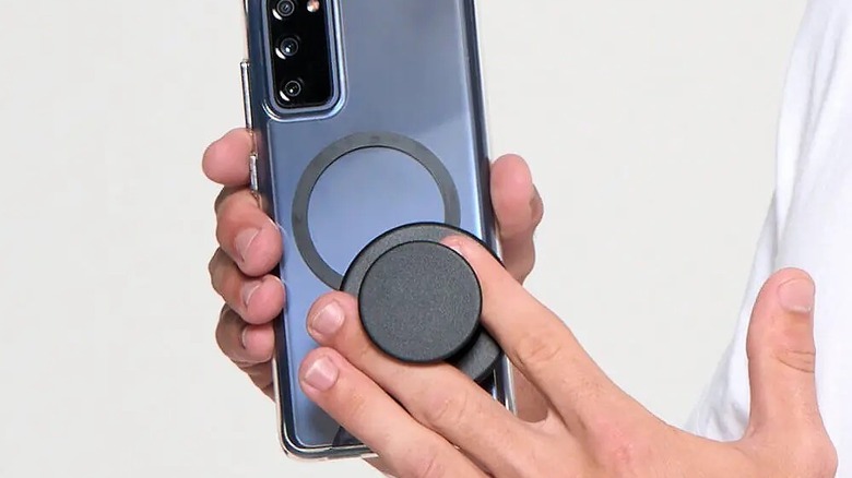 A person attaching PopSockets Phone Grip for MagSafe to an Android phone