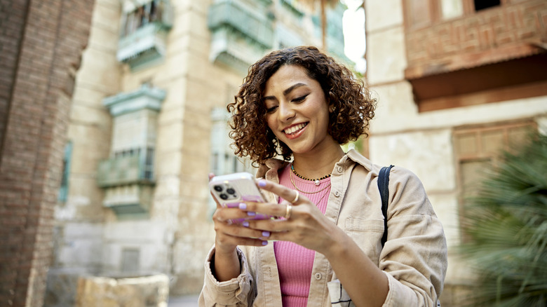 A woman using an Android phone with city buildings in the background