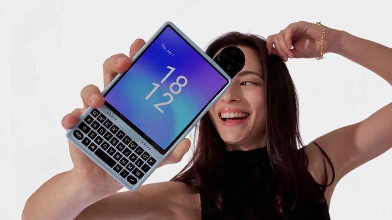 Person holding the Ikko MindOne Pro with its snap-in QWERTY keyboard case attached.