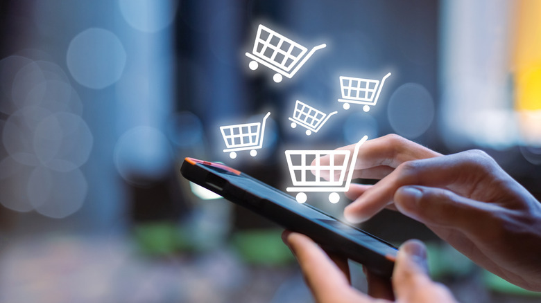 person buying things on a smartphone, concept, digital shopping cart icons floating in air above smartphone