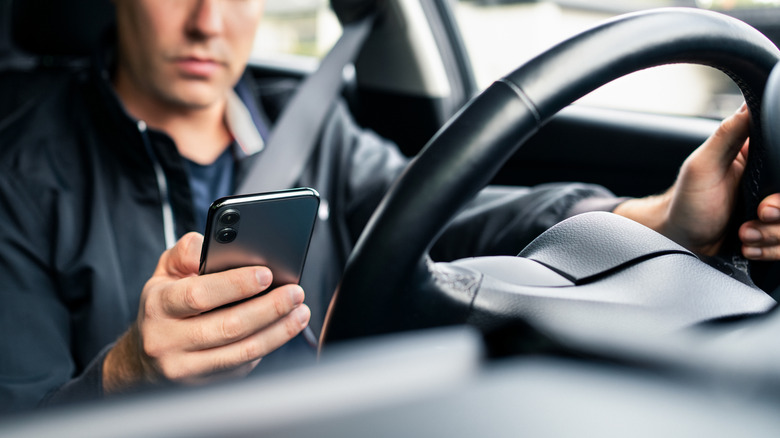 person driving car with phone