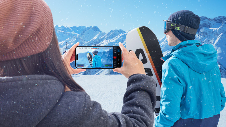 A person using the Blackmagic Camera app to record a snowboarder