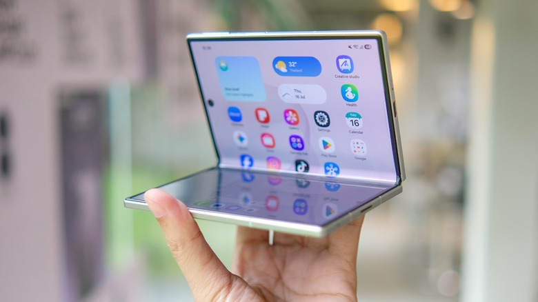 Close-up of a person hgolding the Samsung Galaxy Z Fold 8 smartphone in partially unfolded state