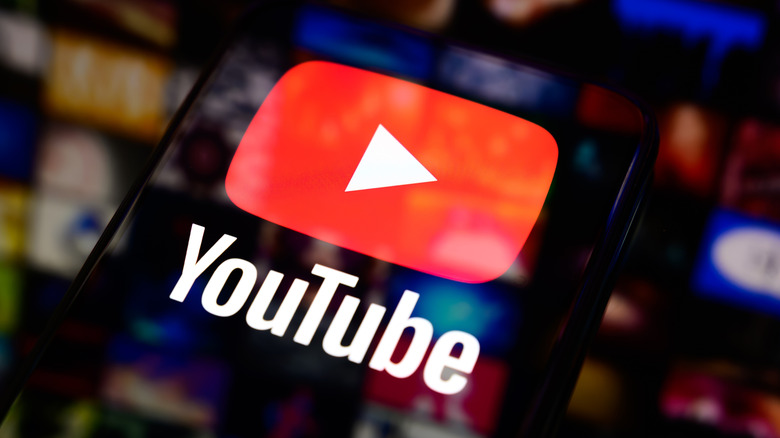 YouTube logo glowing brightly on a mobile phone screen in a dark setting