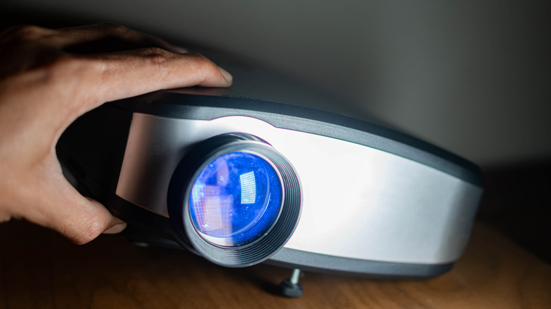 A hand moving a home projector