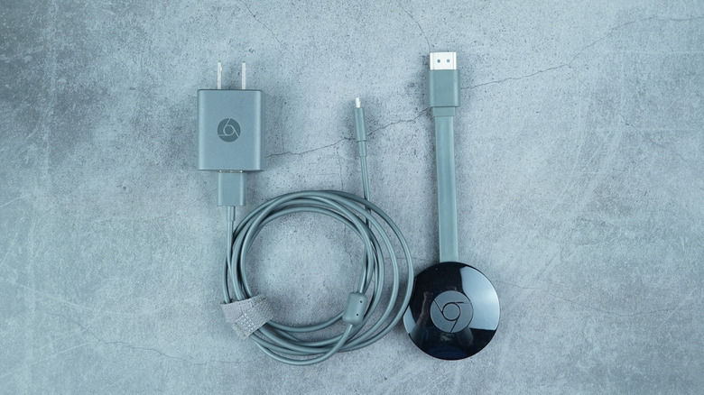 A Google Chromecast device set against a gray backdrop.