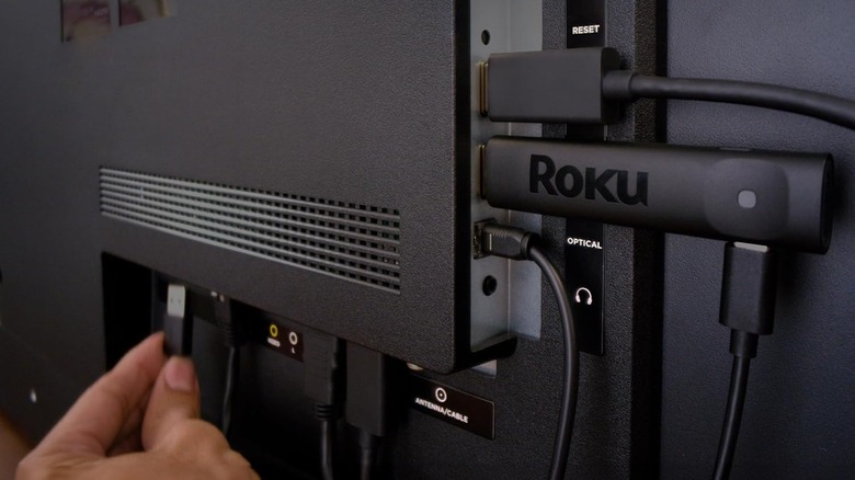 A person plugging in the USB power of the Roku Streaming Stick Plus into their TV.