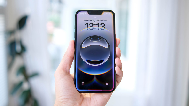 A hand holding an iPhone 16e with the screen locked