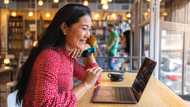 A woman having a video call via laptop, at a modern and cozy cafeteria