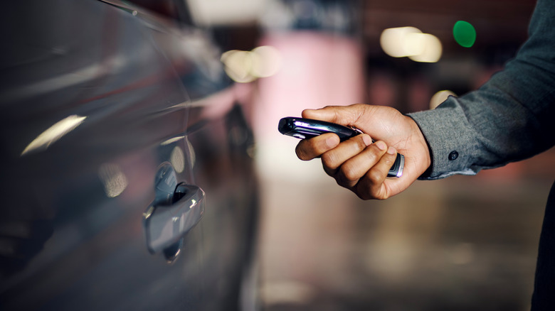 Man's hand pressing a button to unlock the vehicle door on a modern car key
