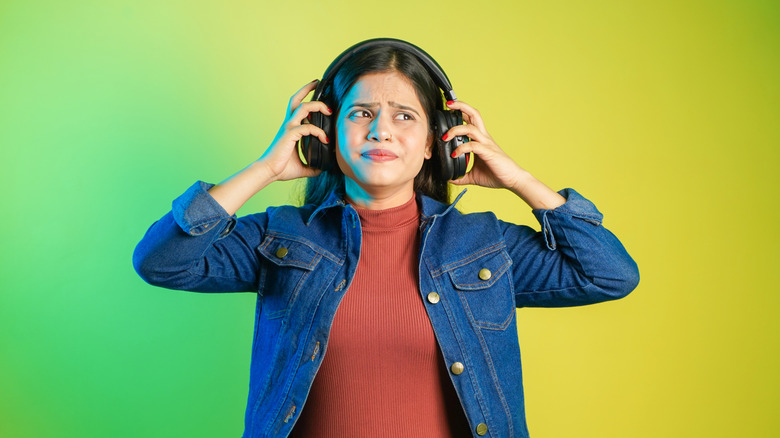 An angry looking woman with a pair of headphones on
