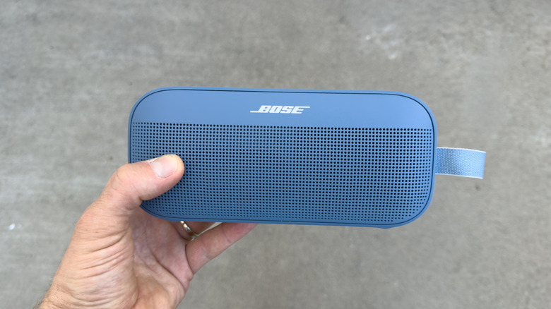 A person holding a Bose portable Bluetooth speaker.