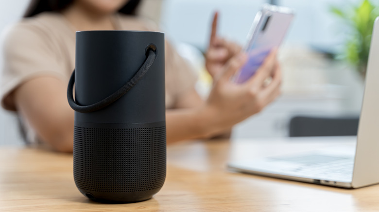 A person using the Bose Portable Smart Speaker while browsing on a smartphone