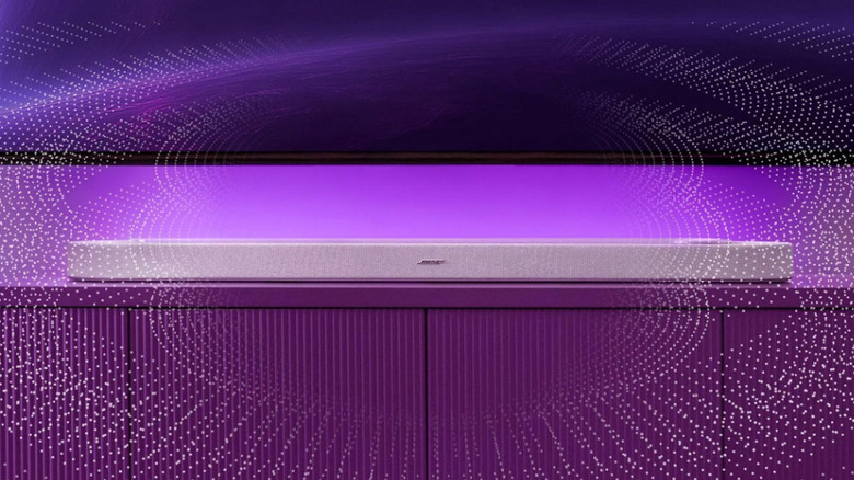 The Bose Lifestyle Ultra Soundbar under a TV, in front of a purple backlight