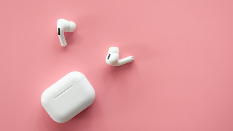 AirPods out of their case on a solid pink background