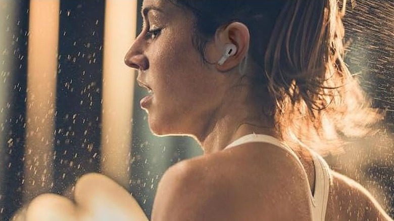 Close up of a woman running while wearing AirPods that are connected to ear hooks