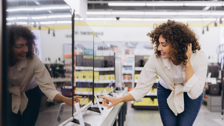 A person shopping for TVs at a retail outlet.