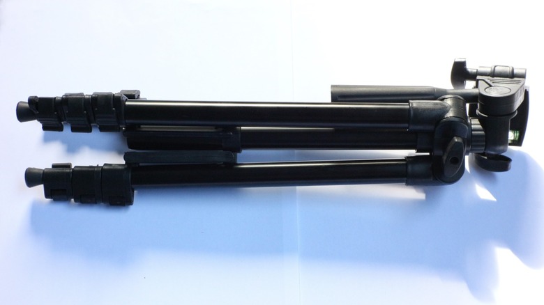 a cheap tripod lying on its side on a white background