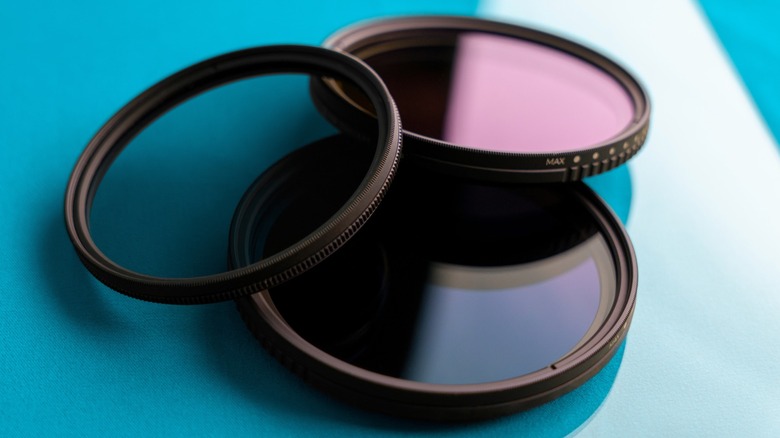 a set of camera filters, including a variable ND filter, placed on a blue surface