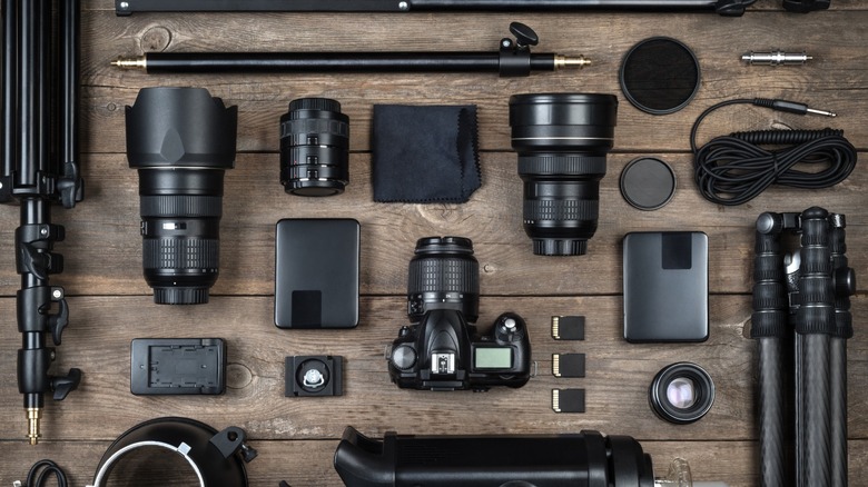 a camera, lenses, and several accessories laid out on a wooden surface