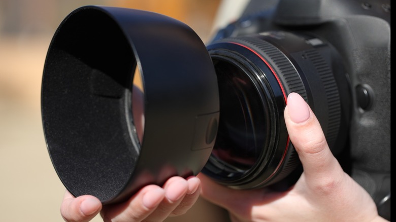 a photographer installing a massive lens hood on a camera