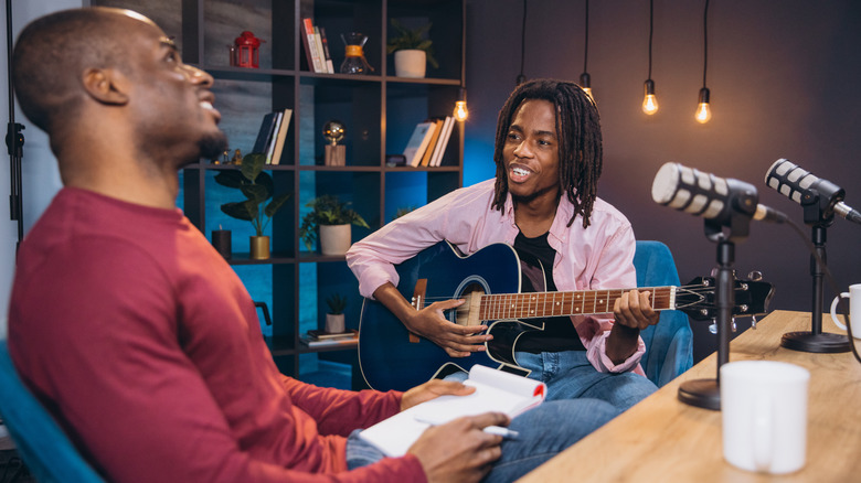 Two men in a studio, one with a guitar.