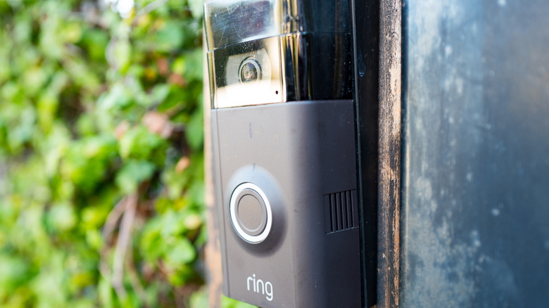 A close-up image of a Ring video doorbell mounted to an exterior door frame.
