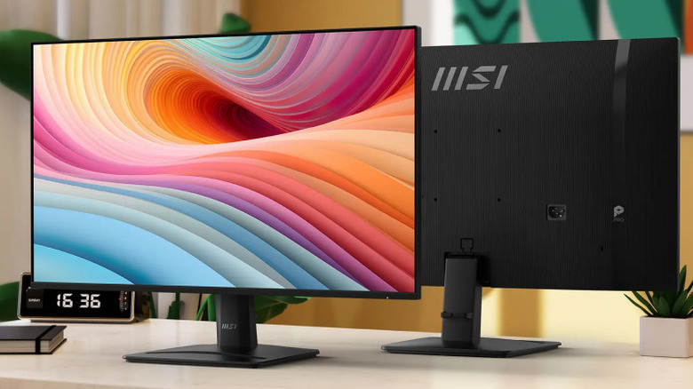 MSI Pro MP251W E2 monitor facing toward camera on desk, clock visible in background, back of monitor visible behind