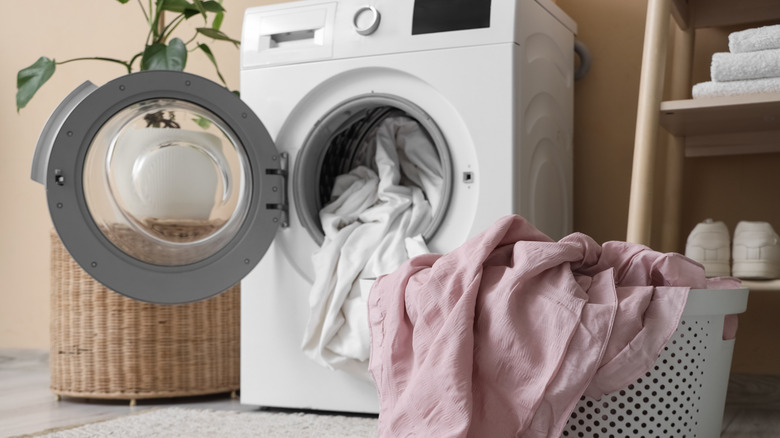 A washing machines with bed sheets in it.