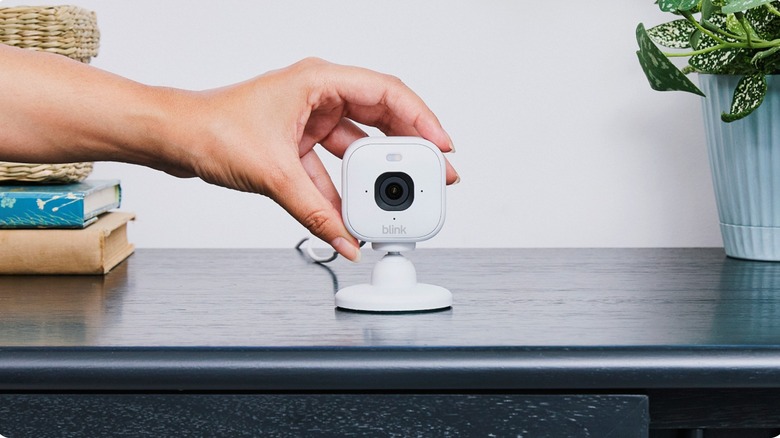 A person touching the Blink Mini 2K+ camera with their fingers