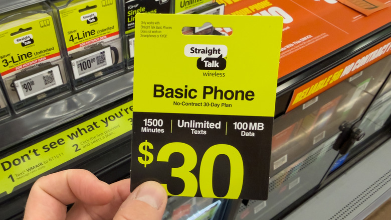 A hand holding a sealed Straight Talk gift card.
