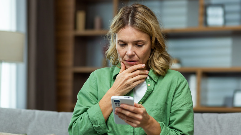 woman looking at smartphone, look of confusion on her face