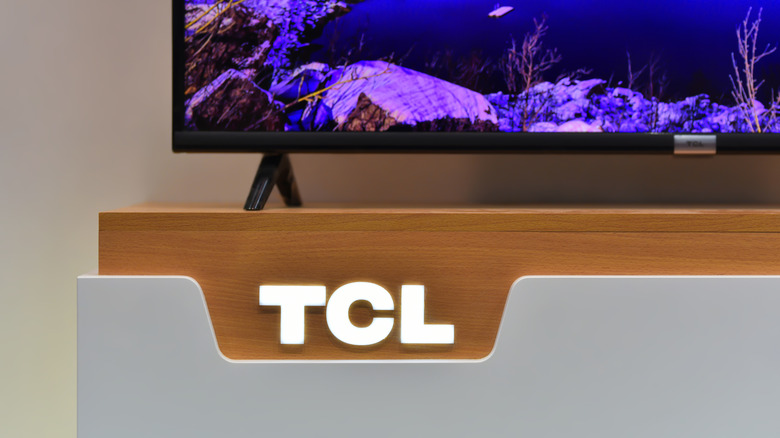 The TCL logo lit up beneath a smart TV