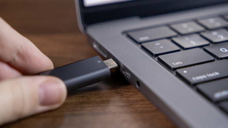 Person inserting a USB flash drive to a laptop's USB port