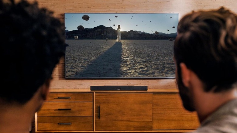 The Bose Smart Soundbar 600 placed below a wall-mounted TV on a TV stand.