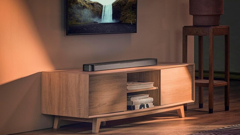 The JBL Bar 300MK2 placed below a wall-mounted TV on a TV stand.