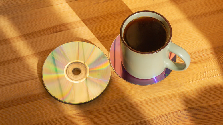 A coffee mug sitting atop a CD used as a coaster