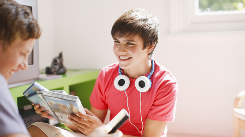 Two people smiling as they go through a DVD collection