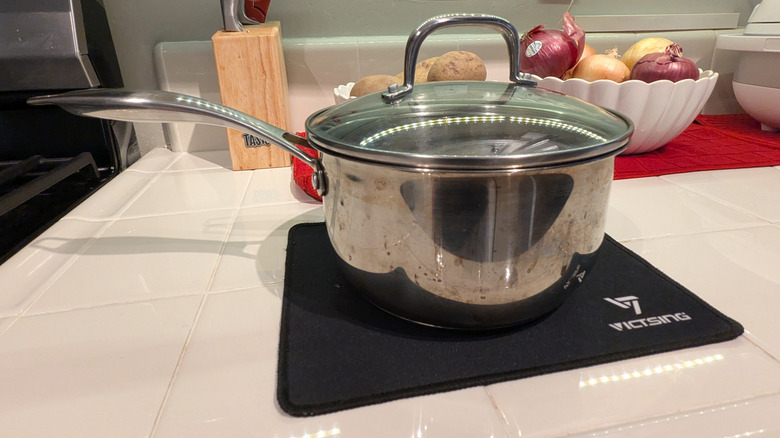 Cooking pot sitting on top of a mouse pad on tile countertop