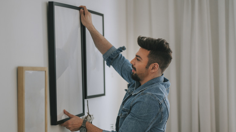 person hanging a painting on the walll