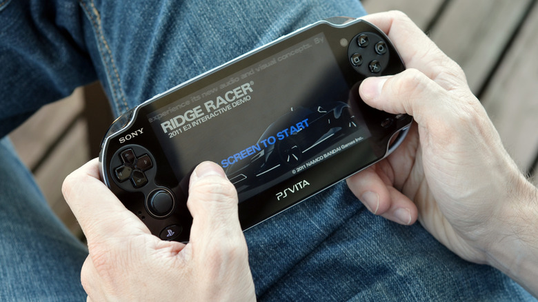 A person sitting playing Ridge Racer on the PlayStation Vita