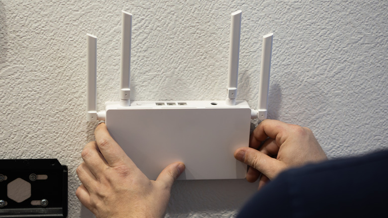 Person installing a wireless router on a wall