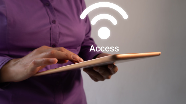 Woman holding smart tablet with wi-fi signal icon floating above it, Access written in white