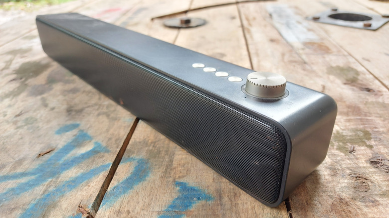 A soundbar placed on a flat surface connected using a cable