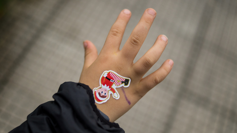 Child's hand with elf sticker on top