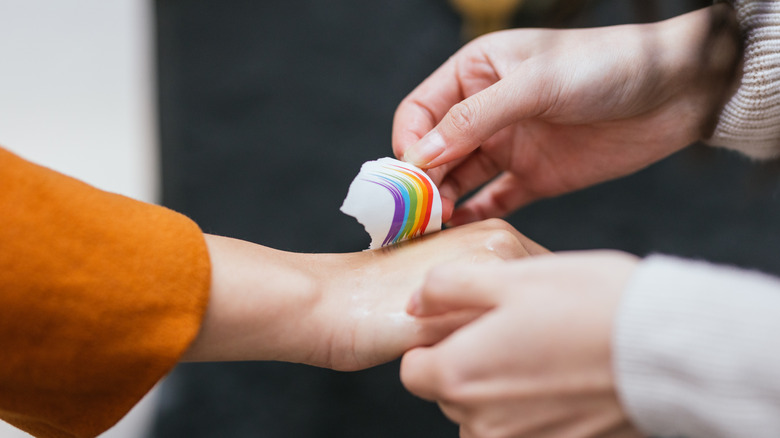 Close-up of person applying temporary rainbow tattoo to hand