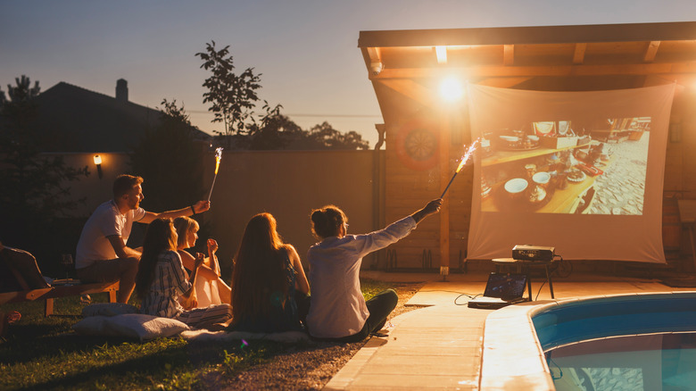 A family gathers around a movie by the pool
