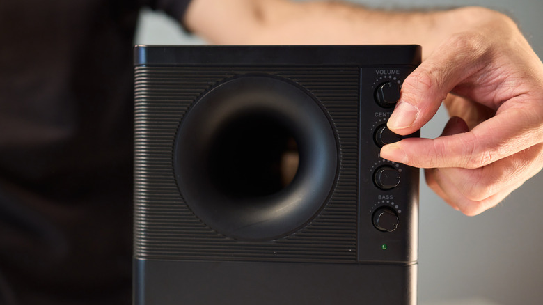 Person adjusting knobs on a subwoofer